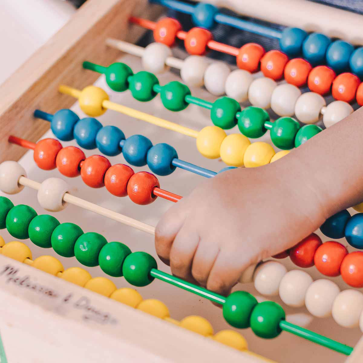 Pédagogie active et développement de l’autonomie – Kids Club Swiss Crissier  Enfant jouant avec un abaque coloré – Activité éducative pour développer la motricité et l'autonomie